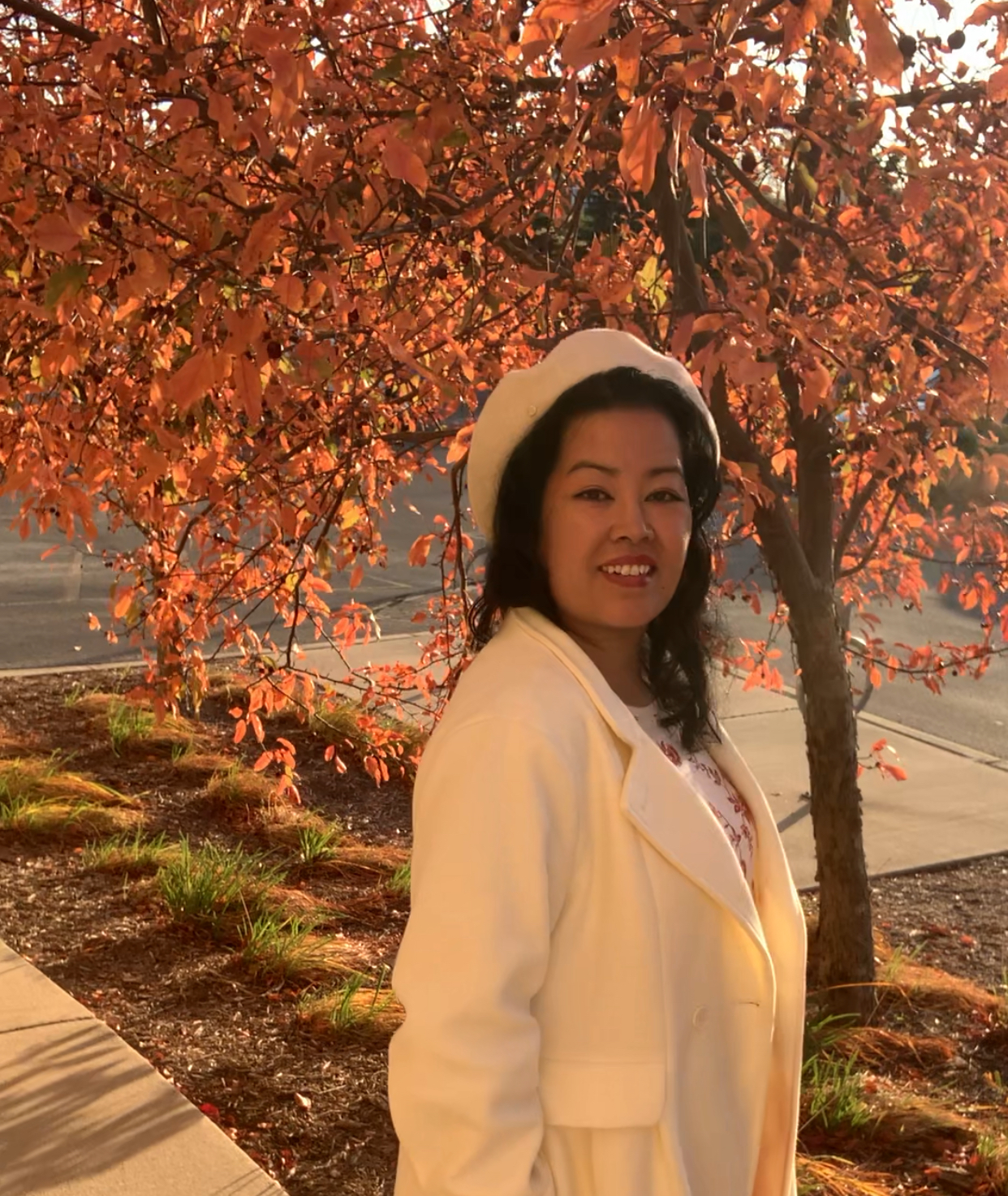 Judy is smiling under an autumn tree